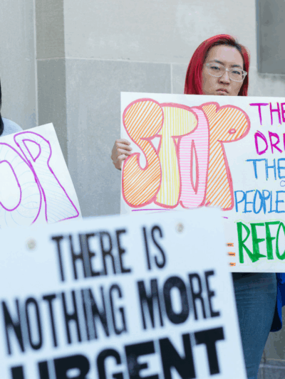 Protesters holding signs that say Stop The War on Drugs, the war on people of color, reform now.