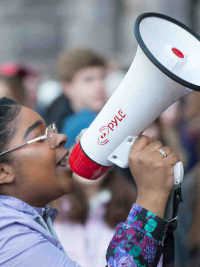 A student holding a speaker while attending a protest