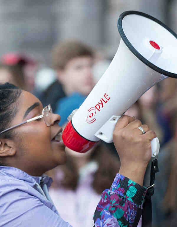 A student holding a speaker while attending a protest