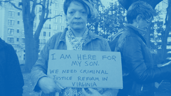 a woman holding a sign that says "I am here for my son. We need criminal justice reform in Virginia"