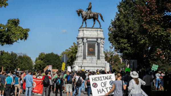 Protest on Monument Avenue, Richmond with a woman holding a sign that says "Heritage of Hate" in the foreground