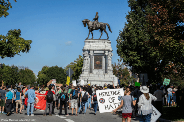 Protest on Monument Avenue, Richmond with a woman holding a sign that says "Heritage of Hate" in the foreground