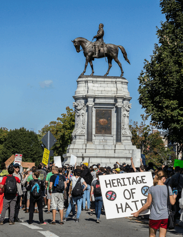 Protest on Monument Avenue, Richmond with a woman holding a sign that says "Heritage of Hate" in the foreground