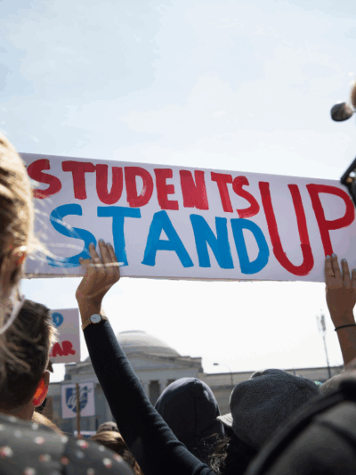 A student held a sign saying "Students Stand Up" in red and blue at the March for Our Lives in 2018