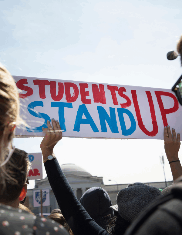 A student held a sign saying "Students Stand Up" in red and blue at the March for Our Lives in 2018
