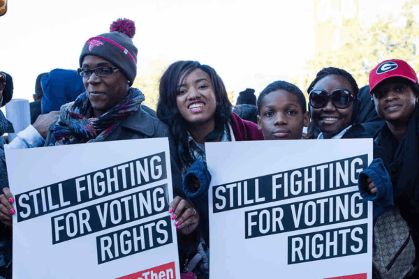 a group of black voters held signs that say "still fighting for voting rights"