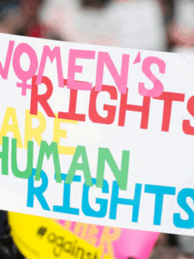 picture from the 2018 Women's March in Richmond, of a dark-skinned woman holding a sign that said "women's rights are human rights" and another white woman holding a sign that said "Power to the Polls"