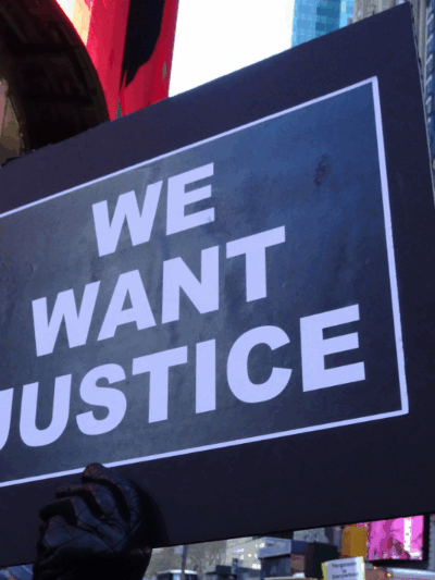 a protest sign that says "We Want Justice"