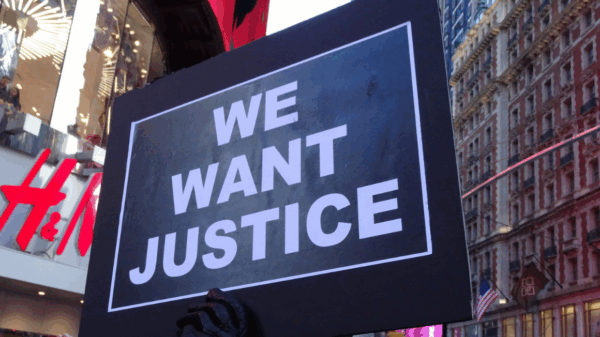 a protest sign that says "We Want Justice"