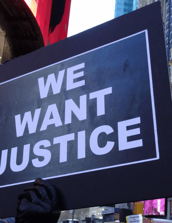 a protest sign that says "We Want Justice"