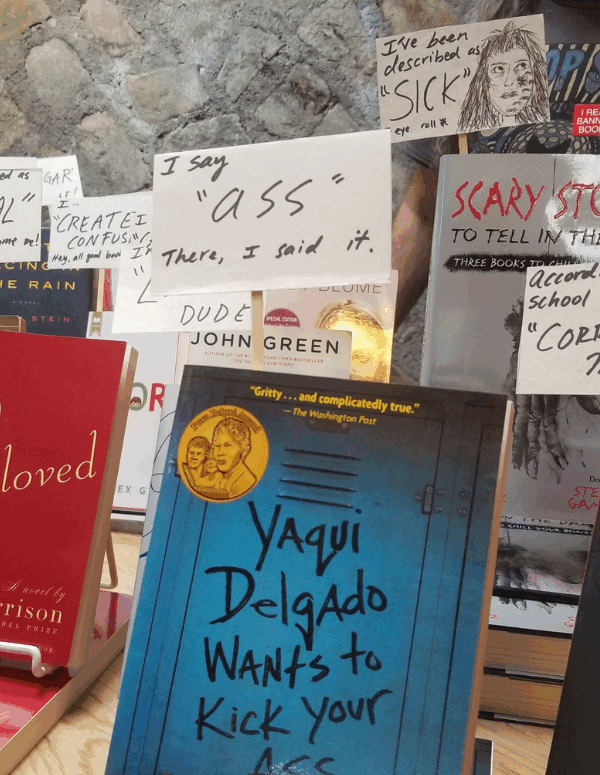 A display of banned books in which the books look like they are holding protest signs about the reasons why they were banned or challenged