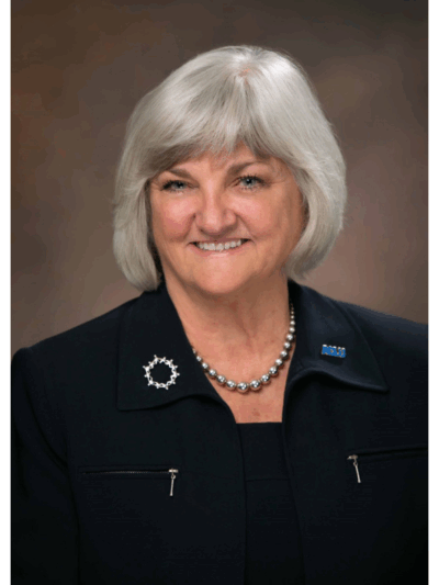 portrait of our executive director Claire Gastanaga, with shoulder length silver hair, round face, blue eyes, and wearing all black.