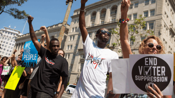 protesters holding signs that say "End Voter Suppression" and "Respect my Vote"