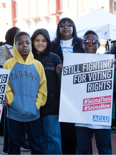 A group of black youths holding signs that say "still fighting for voting rights"