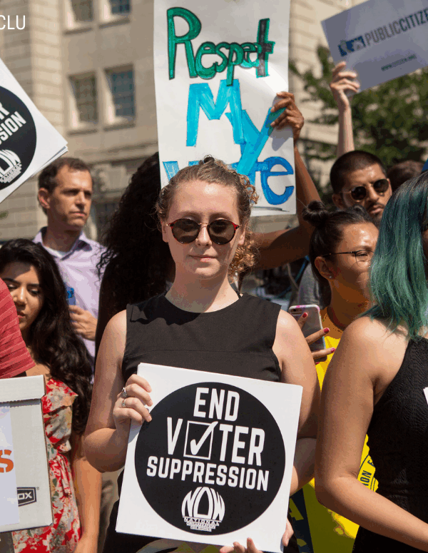 protesters holding signs that say "respect my vote" and "end voter suppression"