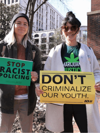 two protesters holding signs that say "Stop racist policing" and "Don't criminalize our youth"