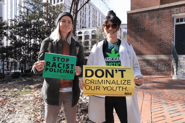 two protesters holding signs that say "Stop racist policing" and "Don't criminalize our youth"
