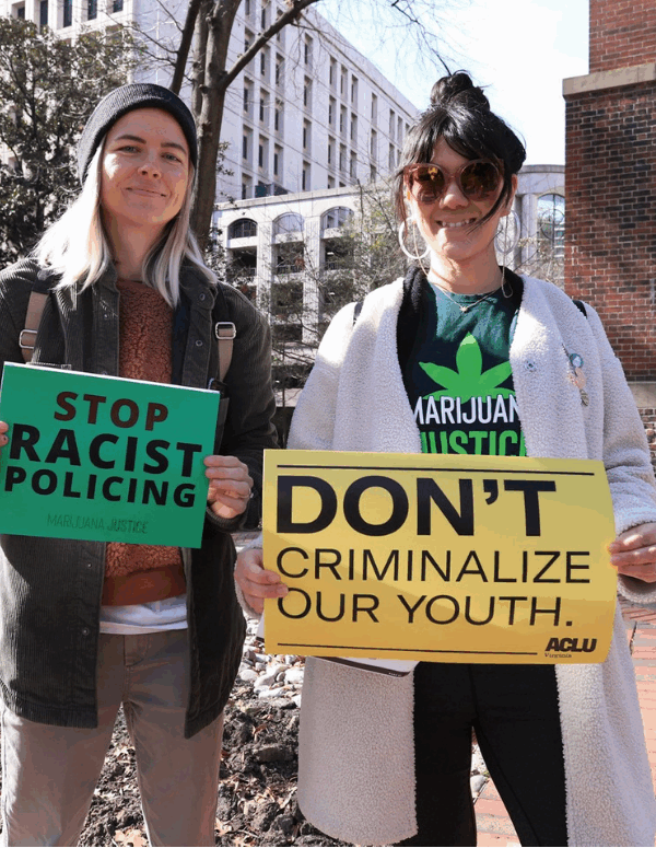 two protesters holding signs that say "Stop racist policing" and "Don't criminalize our youth"