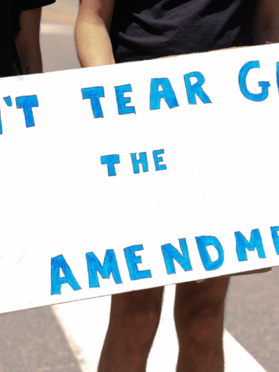 a white sign with blue text that says "don't tear gas the first amendment"
