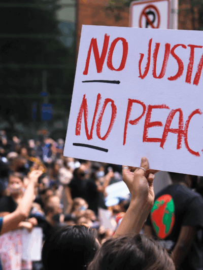 a white protest sign with the text in red "No Justice No Peace"