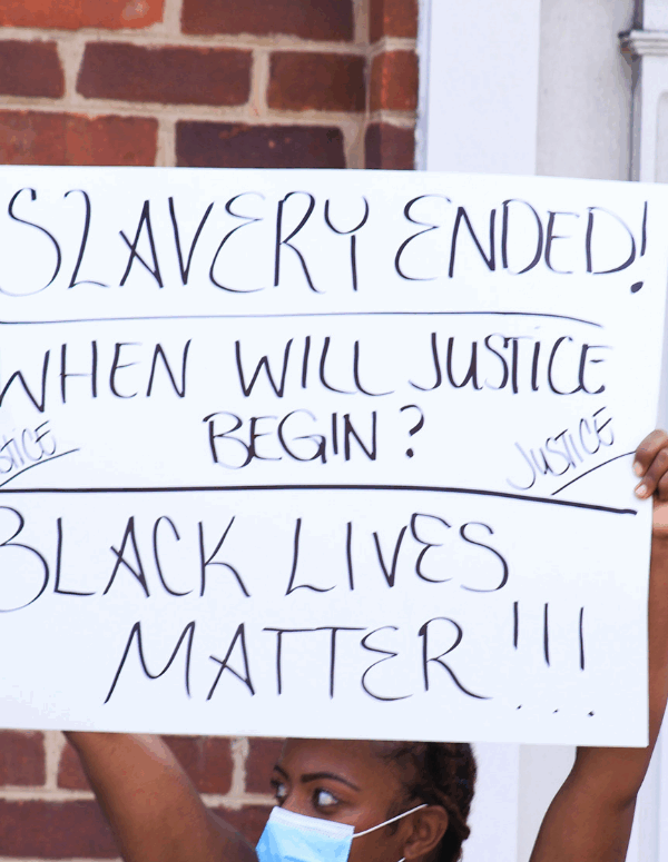Black woman holding a protest sign that says "slavery ended, when will justice begin? Black lives matter!!!{"