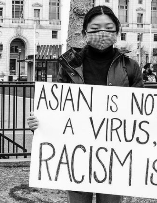 an Asian woman held a sign that says "Asian is not a virus, racism is"