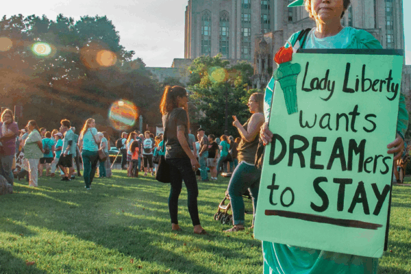 a protester dressed as Lady Liberty held a protest sign that says "Lady Liberty Wants Dreamers to Stay."