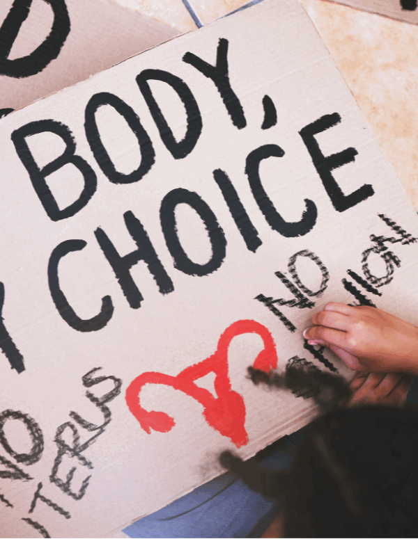 A protester in the process of writing on their sign, which reads "my body, my choice, no uterus, no opinion."