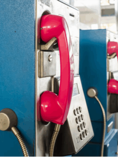 pay phone booths in prison with red phone over blue booth.