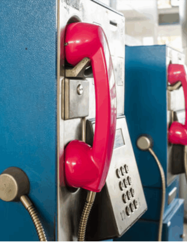 pay phone booths in prison with red phone over blue booth.
