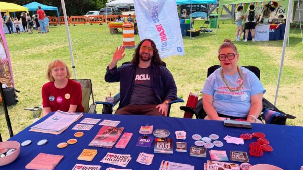 ACLU-VA Organizing team at our table full of swag and literature at a Pride event