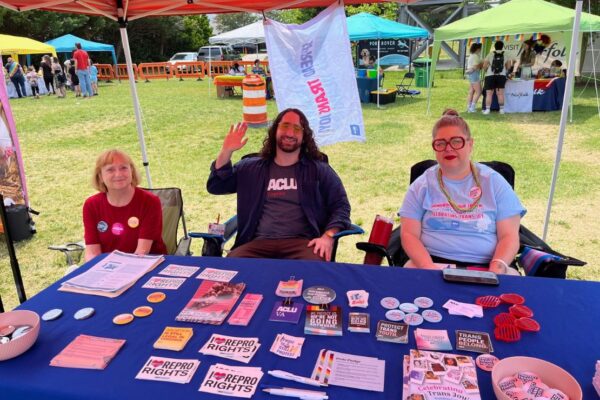 ACLU-VA Organizing team at our table full of swag and literature at a Pride event