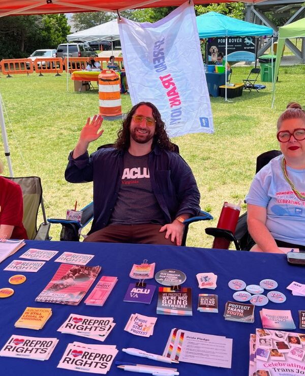 ACLU-VA Organizing team at our table full of swag and literature at a Pride event