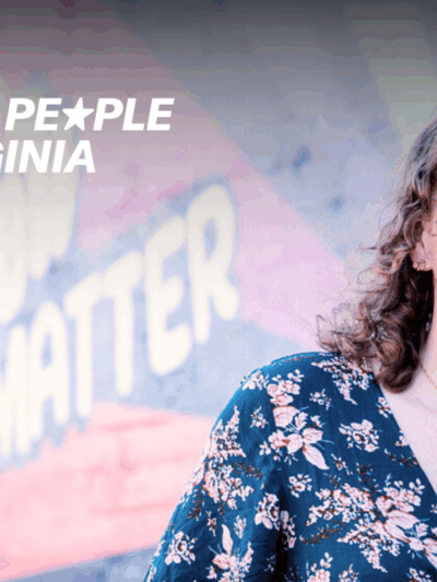 A woman faces towards a camera smiling, in front of a mural. In the top right corner is a logo that says "ACLU of Virginia We the People of Virginia."