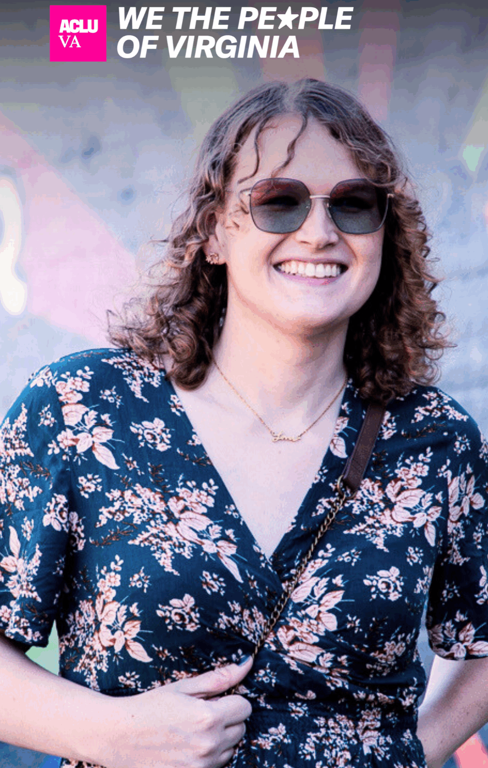 A woman faces towards a camera smiling, in front of a mural. In the top right corner is a logo that says "ACLU of Virginia We the People of Virginia."