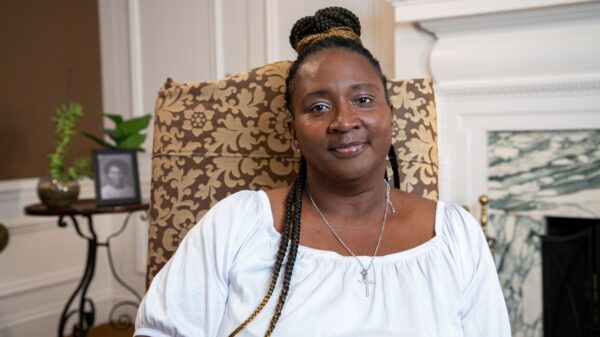 Angela White wears her braids and a white blouse smiling at the camera