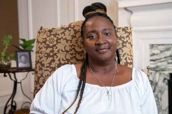 Angela White wears her braids and a white blouse smiling at the camera