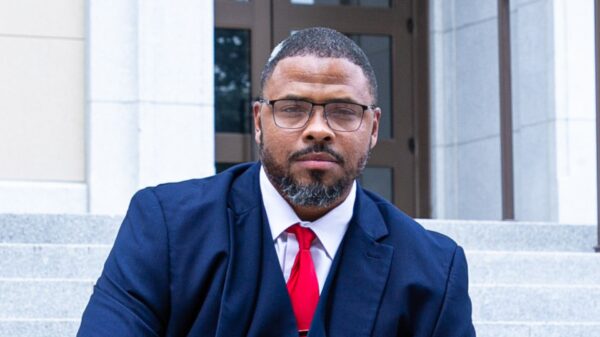 Shawn Barksdale dressed in a navy suit with red tie smiling at the camera