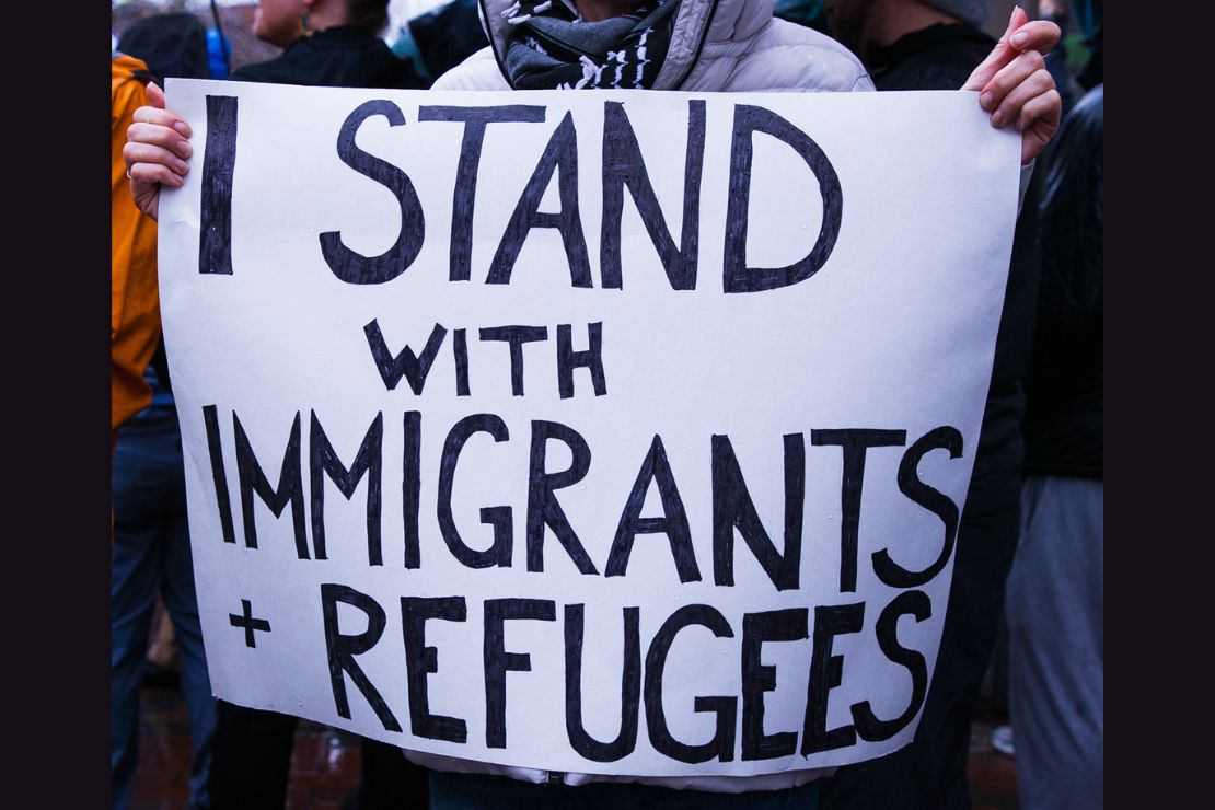 protest signs with the message "I stand with immigrants and refugees"