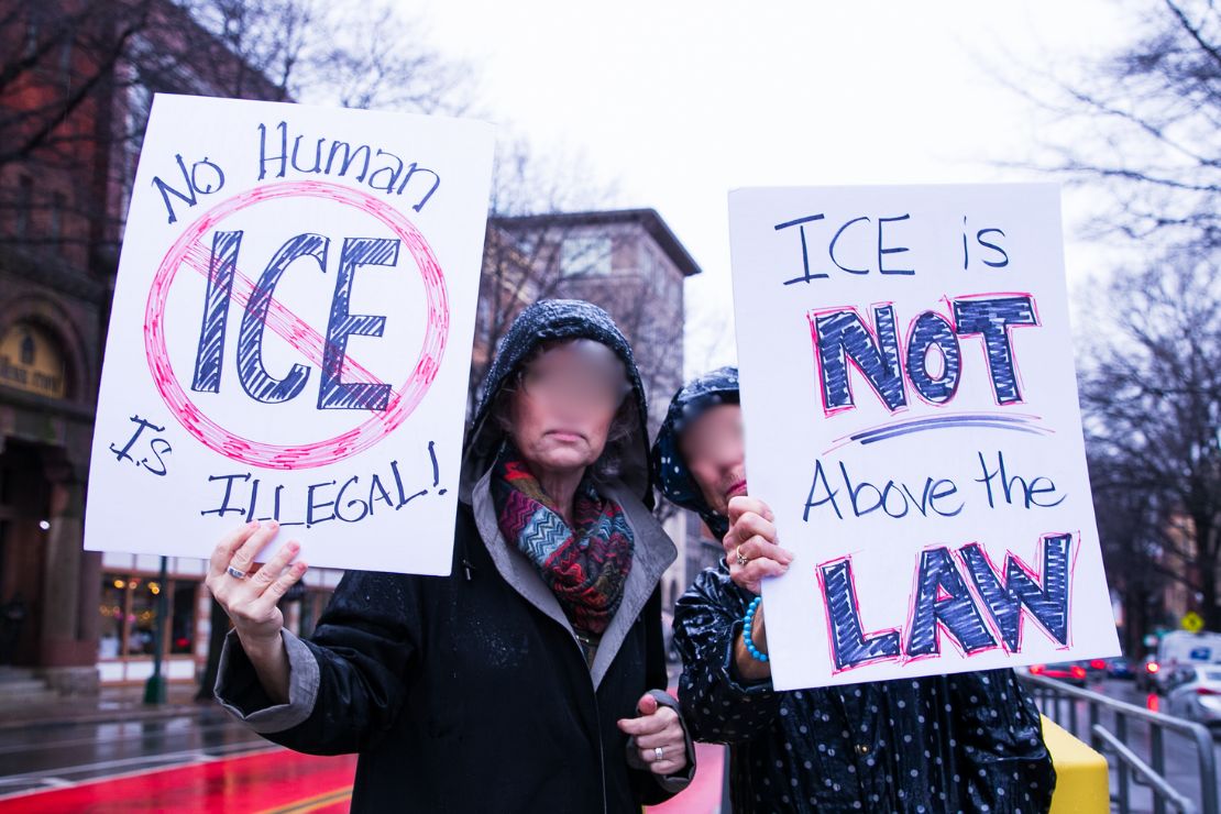 Two protesters stand side by side with the following signs "No human is illegal" and "ICE is not above the law."