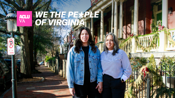 Two people on a cozy sunny sidewalk look towards a camera smiling.