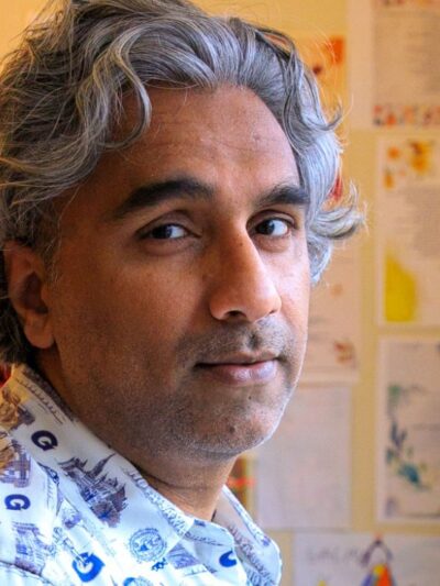 Dr. Badar Khan Suri, with wavy pepper hair, stands in his living room