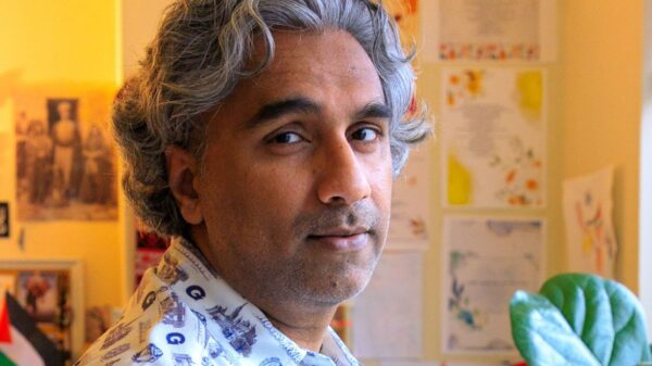 Dr. Badar Khan Suri, with wavy pepper hair, stands in his living room