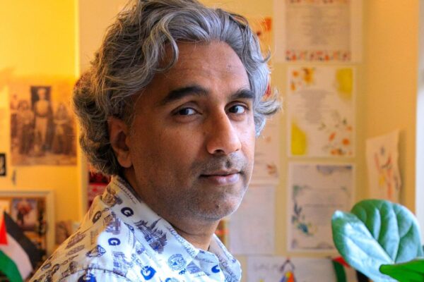 Dr. Badar Khan Suri, with wavy pepper hair, stands in his living room