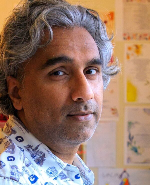 Dr. Badar Khan Suri, with wavy pepper hair, stands in his living room