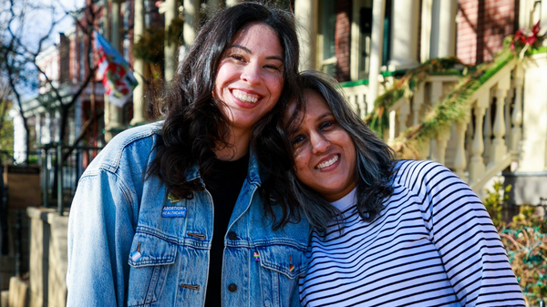 Two women smile towards a camera.
