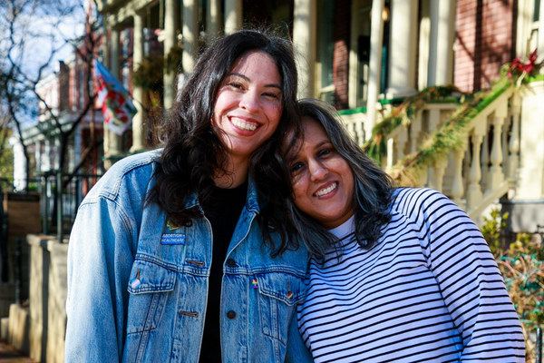 Two women smile towards a camera.