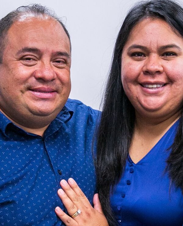 Pastor Manuel and his wife Laura, wearing matching blue, smile warmly at the camera