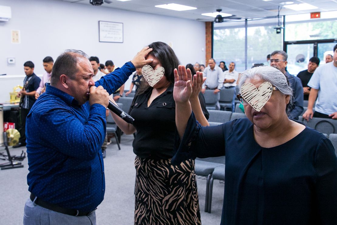 Pastor Manuel prays for two women in his church