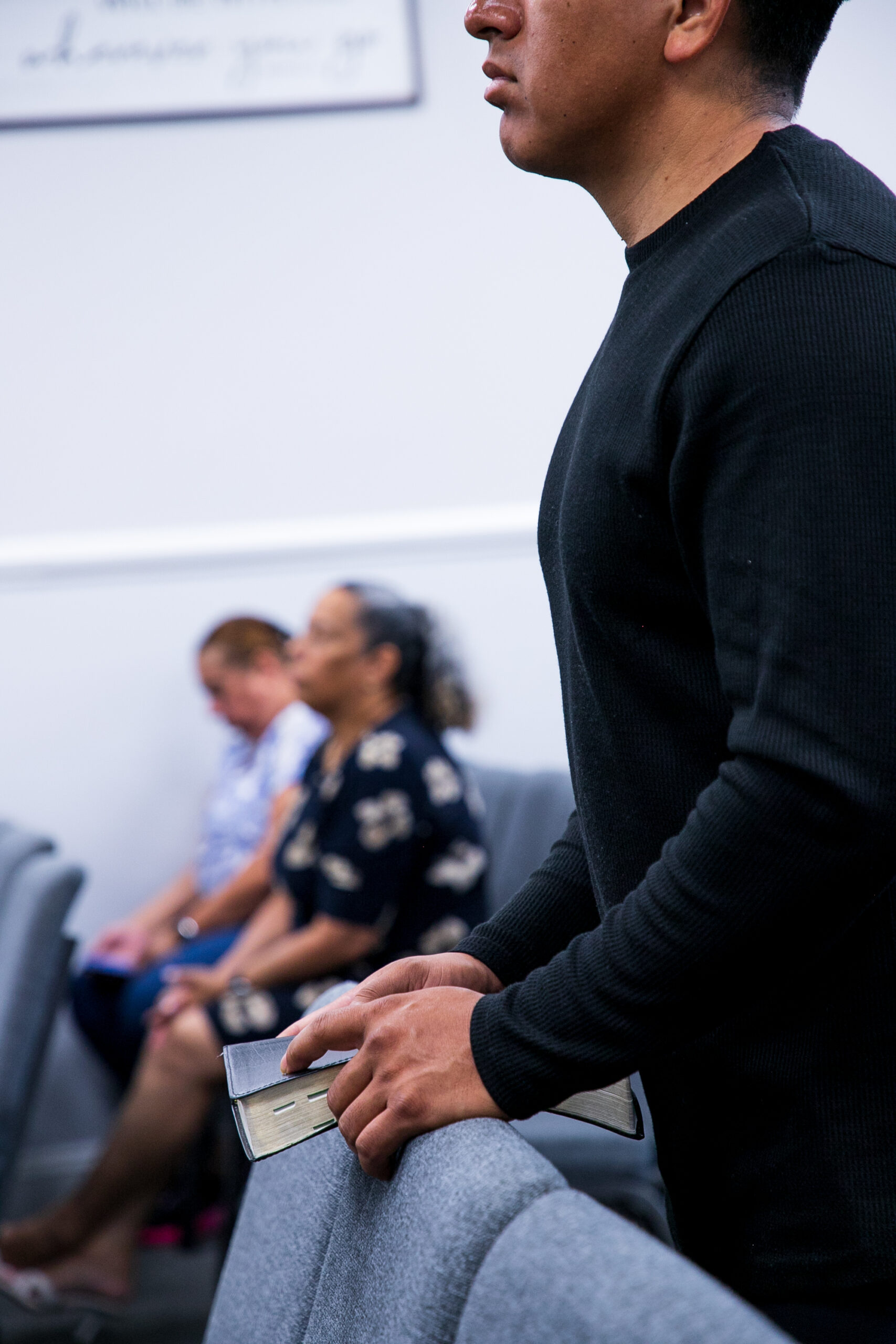 a brown-skin man wearing black hold on to his bible during church